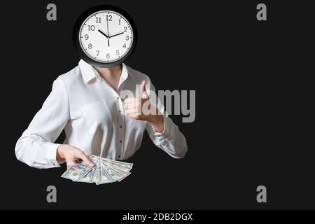 Zeitmanagement mit Wecker mit Kopf Frau in weißer Bluse hält 100 Dollar Scheine, Daumen hoch, großes Zeichen, isoliert auf schwarzem Hintergrund, Vorderansicht Stockfoto