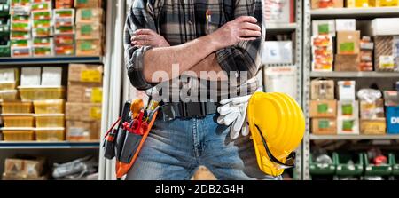 Technischer Elektriker im Laden von elektrischen Komponenten mit gekreuzten Armen. Bauindustrie, Elektrik. Stockfoto