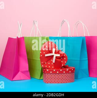 Roter Papierkasten mit Geschenk- und Papiertüten für den Einkaufsstand auf pink-blauem Grund Stockfoto