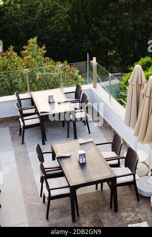 Gewattte Tische und Stühle auf der Terrasse Sommercafé mit Blick auf den grünen Park. Draufsicht. Stockfoto