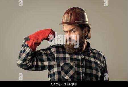 Er ist stark. Industriearbeiter in Helm. Mann in Handschuhen. Bauarbeiter in Hut. Ingenieur Architekt arbeiten in Schutzhelm. Brutaler Techniker Baumeister. Fabrikarbeiter Mechaniker. Stockfoto