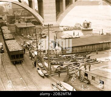 Kanus gibt es im Überfluss als Flutwasser das Ufer unter Betonbrücke und neben Eisenbahnhopper Autos.. Stockfoto