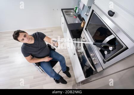 Deaktivierter Mann, Der Mit Dem Grabber-Werkzeug Die Mikrowelle In Der Küche Steuern Kann Stockfoto