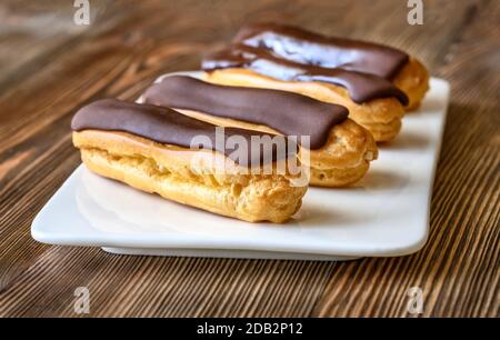 Eclairs mit Schokoladenauffüllen auf Servierplatte Stockfoto