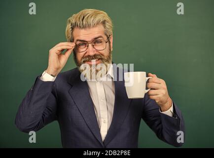 Optimistisches Konzept. Lehrer in der Brille trinken Kaffee Kelkboard Hintergrund. Angenehmer Schluck. Kaffeepause und Entspannung. Mittagszeit für Lehrer. Kaffeesüchtig. Energieaufladung für den ganzen Tag. Koffeindosis. Stockfoto