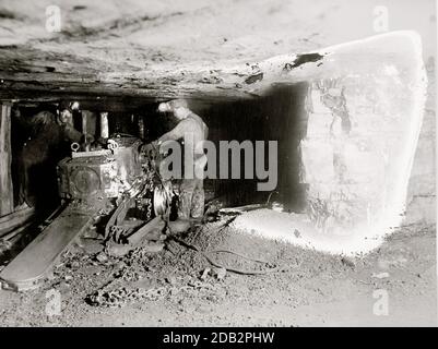 Miner betreibt Minenmaschinen, die zur Ausguckung eines horizontalen Schachts betrieben werden. Stockfoto