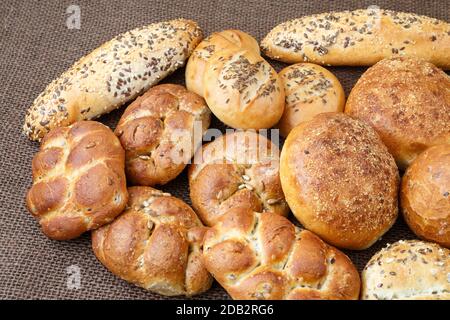 Verschiedene Arten von Vollkorn Brot und Brötchen auf braunem Hintergrund Stockfoto