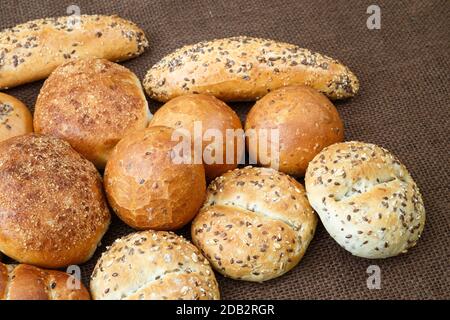 Verschiedene Arten von Vollkorn Brot und Brötchen auf braunem Hintergrund Stockfoto