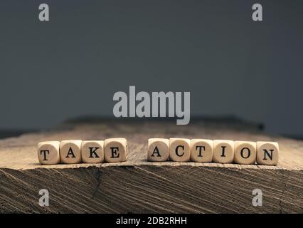 Die Worte Handeln auf kleinen Holzblöcken auf einem Holztisch mit Platz für Text oder Bild Stockfoto