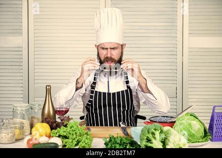 Kulinarisch ist es spannend. Chefkoch mit hübscher Hipster. Mach dich fertig. Mann bärtigen Koch immer bereit Kochen leckeres Gericht. Koch bei der Arbeit, der die Schicht beginnt. Kerl in professioneller Uniform bereit kochen. Konzept des Chefkochs. Stockfoto