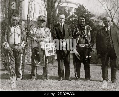 Präsident Calvin Coolidge posierte, in voller Länge Porträt, stehend, nach vorne, mit vier Osage-Indianern; Weisses Haus im Hintergrund.. Stockfoto