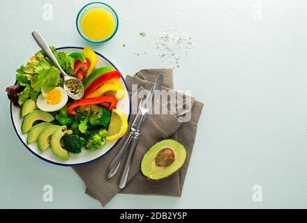 Gesundes Salatessen mit Quinoa, Ei, Avocado und gemischtem frischem Gemüse auf blauem Grund Draufsicht. Lebensmittel und Gesundheit. Gesundes Essenskonzept Stockfoto