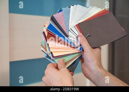 Der Mann wählt das Farbdekor der neuen Möbel aus farbigen Mustern im Möbel- und Bodengeschäft Stockfoto