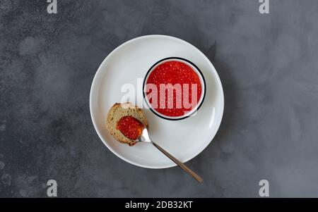 Roter Kaviar auf einem Teller, Meeresfrüchte-Delikatessen. Dunkler Hintergrund. Draufsicht. Kopierraum. Stockfoto