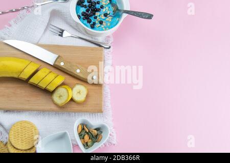 Bananenscheiben auf einem Holztablett, neben der Salatschüssel Mandel-Sandnüsse und Kürbiskerne. Stockfoto