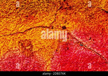Oberflächentextur mit gelber orange und roter Farbe auf einer gerissenen Oberflächenstruktur. Für abstrakte Hintergründe. Deutschland Stockfoto