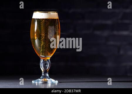 Eine Tasse Stella Artois voll von Bier mit einem Schwarzer Backstein Hintergrund Stockfoto