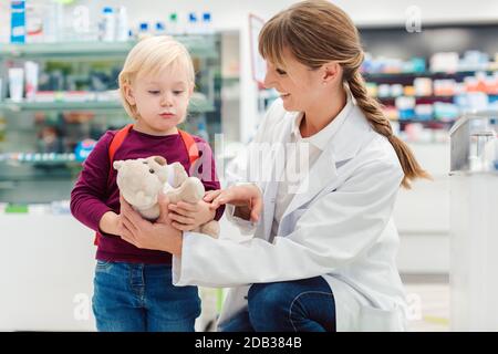 Apotheker Frau mit Kind Kunden und ihre Plüsch Spielzeug in der Pharmazie Stockfoto