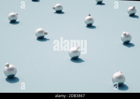 Silber matt Weihnachtskugeln regelmäßig auf blauem Hintergrund verteilt. Weihnachtsschmuck mit Schatten auf strukturierter Oberfläche. Stockfoto