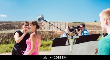 Film- oder Filmset mit Modell, Mikrofon und Assistent während einer Produktion Stockfoto