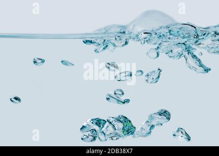 Vollformatansicht aufsteigender Luftblasen im Medium Wasser vor hellblauem Hintergrund. Stockfoto