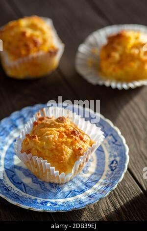 Maisbrot-Muffins mit Cheddar-Käse auf einem Blue Vintage Teller auf einem Holzhintergrund - FOODPIX Stockfoto