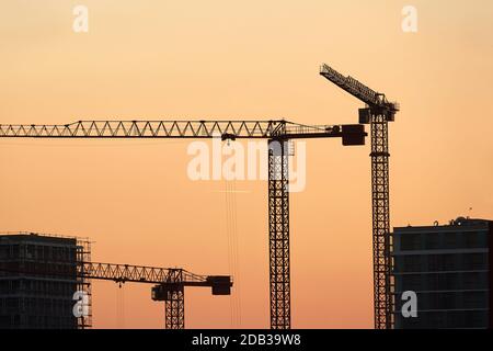 Baukräne gegen dramatische Dämmerung rot glühen Himmel Stockfoto