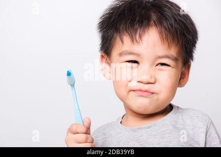 Nahaufnahme asiatisches Gesicht, Kleine Kinder Junge Hand hält Zahnbürste, die er selbst Zähne auf weißem Hintergrund mit Kopierraum, medizinischer Versorgung putzt Stockfoto