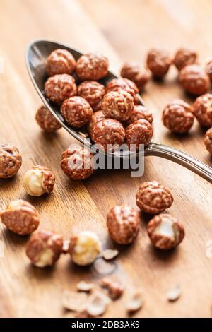 Haselnüsse mit Zuckervereisung im Löffel auf Holztisch. Stockfoto