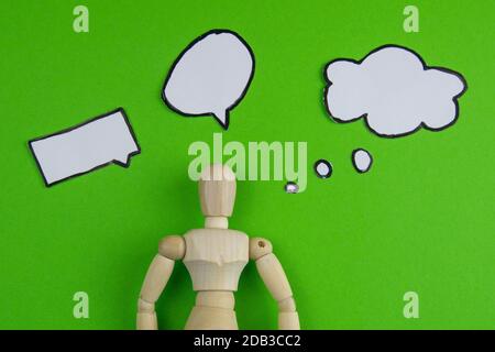 Handarbeit aus Holz Mann Figur Schaufensterpuppe Modell Dummy Puppe mit leeren Sprechblase auf grünem Hintergrund, Objekte, niemand. Stockfoto