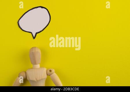 Handgefertigte Holzfigur Mannequin Modell Dummy Puppe mit leeren Sprechblase auf orangefarbenem Hintergrund, Objekte, niemand. Stockfoto