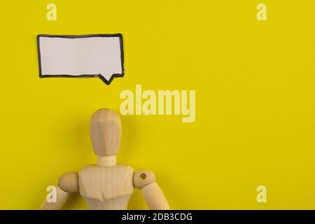 Handgefertigte Holzfigur Mannequin Modell Dummy Puppe mit leeren Sprechblase auf orangefarbenem Hintergrund, Objekte, niemand. Stockfoto