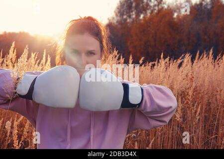 Frau Boxer geht in für Sport auf dem Hintergrund der herbstlichen Natur, Sonnenuntergang auf dem Feld. Sonnenuntergang im Herbstwald Stockfoto