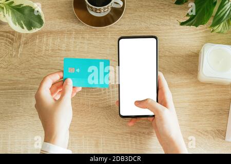 Mockup einer Frau mit Telefon und Kreditkarte auf dem Tisch. Leerer Bildschirm zum Einfügen des Designs. E-Commerce-Konzept Stockfoto