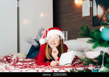 Rothaarige Teenager-Mädchen in einem weihnachtsmann Hut liegen auf die Bett Stockfoto