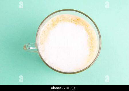 Latte-Kaffee in elegantem transparenten Glas mit Schlagsahne auf dem minzfarbenen Hintergrund. Stockfoto