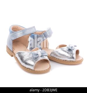 Silberne Kindersandalen für Mädchen mit Schleife auf weißem Hintergrund. Foto für Schuhwerbung Stockfoto