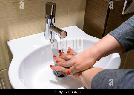 Eine Frau springt mit Seife unter fließendem Wasser in die Hände Stockfoto