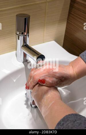 Eine Frau springt mit Seife unter fließendem Wasser in die Hände Stockfoto