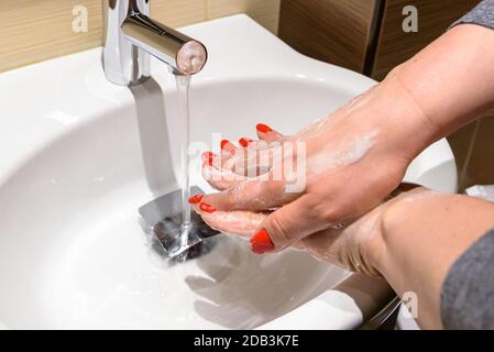 Eine Frau springt mit Seife unter fließendem Wasser in die Hände Stockfoto