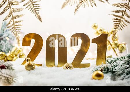 Weihnachten Goldschmuck auf Schnee mit Tannenzweigen, Zahlen 2021 das Symbol des neuen Jahres und weihnachtslichter. Stockfoto