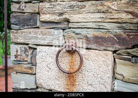 Ring aus Schmiedeeisen an einer Steinmauer mit Rostspuren Stockfoto
