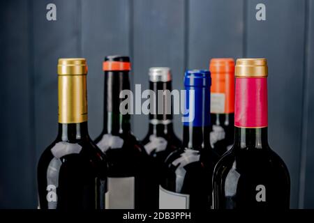 Eingestellt von beschriftet und ungeöffnete Flaschen Rotwein von unterschiedlichen Herstellern mit unterschiedlichen Farbe Etiketten auf grau Holz- Hintergrund Stockfoto