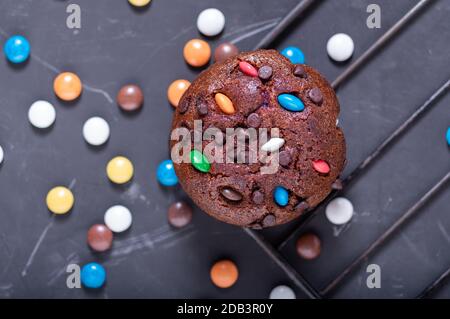 Schokoladenmuffin auf einem Drahtgestell. Muffin bestreut mit bunten Süßigkeiten. Stockfoto