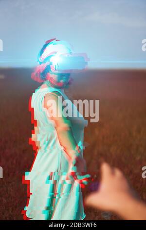 Frau geht in die virtuelle Realität mit Virtual-Reality-Headset. Bild mit Glitch-Effekt. Stockfoto