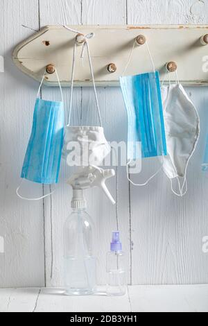 Handgemachte Masken und Flüssigdesinfektion hängen auf weißen Kleiderbügel für Schutz gegen covid-19 Stockfoto