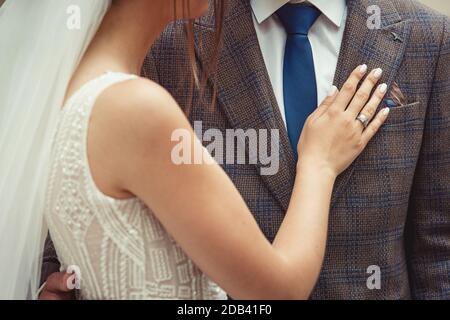 Braut und Bräutigam Hochzeitspaar mit Nahaufnahme auf der Hand der Frau auf der Brust des Mannes. Braun karierte Jacke Stockfoto