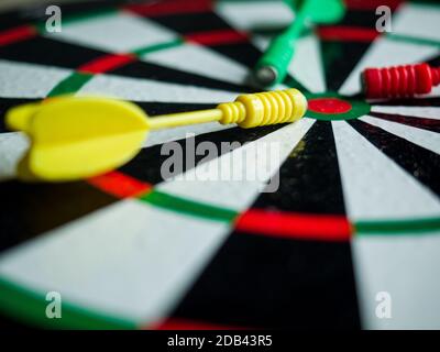 Eine Nahaufnahme von drei farbigen Darts auf einer Dartscheibe Stockfoto