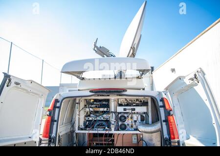 Das sendende Auto mit einer Satellitenantenne auf dem Dach sorgt für die Übertragung des Videosignals über Satellit zum Fernseher. Stockfoto