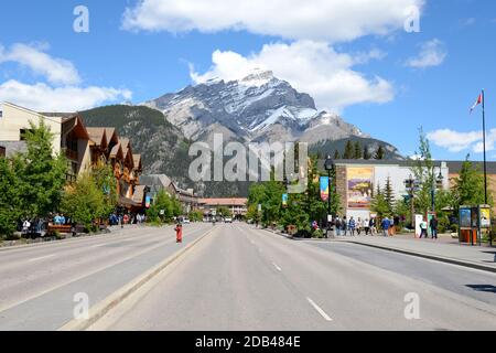 Banff Avenue, die zentrale Straße der Innenstadt von Banff in Kanada an einem sonnigen Tag. Kanadische Touristenstadt mit dem Mount Norquay dahinter. Stockfoto